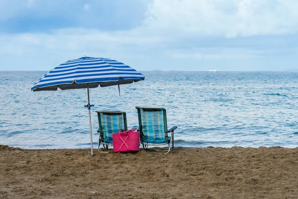 two chairs and one umbrella alone on the beach. High quality photo