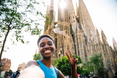 Afrikalı kadın zafer işareti yapıyor. Barselona 'daki Kutsal Aile Kilisesi' ni ziyaret ederken selfie çekiyor.