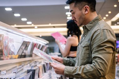  Müşteri bir müzik dükkanında plak plaklarını ve CD 'leri karıştırıyor.