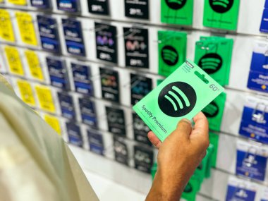 20 Eylül, Barselona, İspanya 2024: Bir el, müzik, oyun ve yayın hizmetleri de dahil olmak üzere çeşitli ön ödemeli kartların yer aldığı bir mağazada Spotify Premium hediye kartı tutuyor.