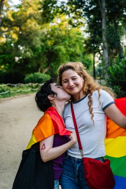Gökkuşağı bayrağına sarılmış iki kadın, aşklarını ve gururlarını kutluyorlar.