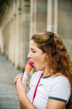 Genç bir kadın yaz tatilinde ferahlatıcı bir dondurma külahının tadını çıkarıyor.