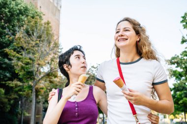 İki arkadaş bir şehir merkezinde yürürken dondurma külahının keyfini çıkarıyorlar, yaz günü keyifli bir sohbet yapıyorlar.