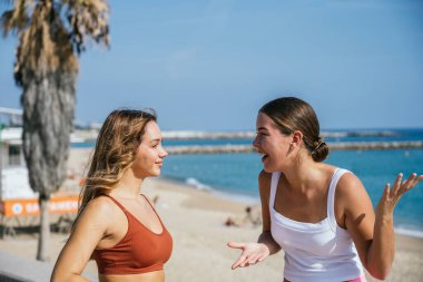 İki bayan arkadaş güzel bir yaz gününde sahilde sohbet ediyorlar.