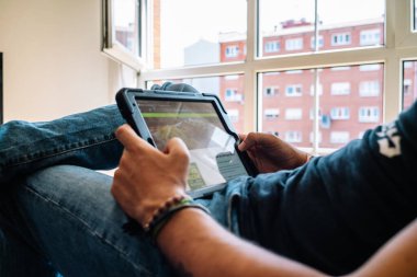 Tablet kullanan, internette gezinen, bilgi arayan, online alışveriş yapan ya da evde haberleri okuyan bir adam