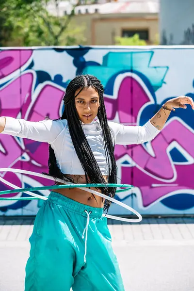 Yetenekli bir sokak dansçısı renkli bir duvar önünde hulahop yeteneğini gösteriyor.