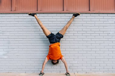 Sporcu, paralel gidonları kullanarak amuda kalkıyor, dayanıklılık, denge ve zindelik gösterisi yapıyor.