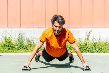 Sporcu spor sahasında şınav çekerek şınav çekiyor. Formda ve güçlü olduğunu gösteriyor.