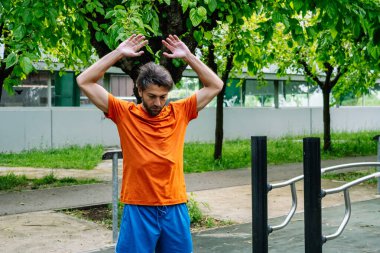 Beyaz tenli sporcu spor salonuna gitmeden önce kollarını esnetiyor.