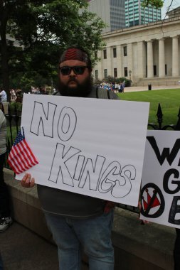 Göstericiler 12 Haziran 2025 'te Columbus State House Lawn' da toplandı. Elinde No Kings mitinginde siyasi ifade ve sosyal farkındalık işaretleri vardı.