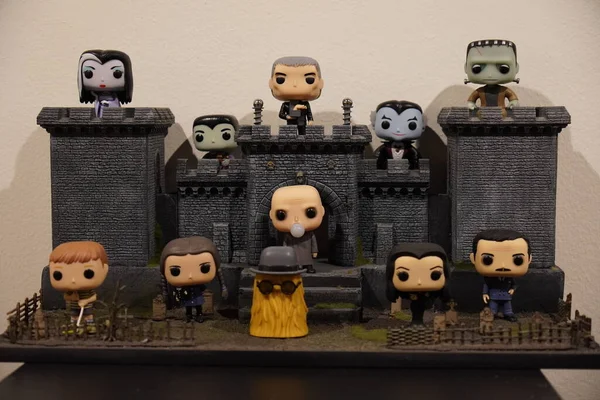 Horizontal shot of a funko pop diorama of the adams family outside a castle in gray and black colors.