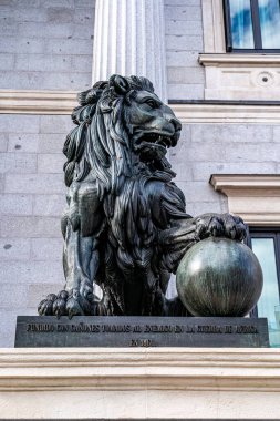 Madrid, İspanya. 15 Nisan 2023. İspanya Kongresi 'nin girişini koruyan bronz aslanlardan birinin dikey görüntüsü, Madrid' de, Afrika Savaşı toplarıyla fırlatılıyor..