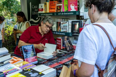 Madrid, İspanya. 16 Haziran 2024. Yazar Juan Manuel de Prada, El Retiro Park 'taki Madrid kitap fuarındaki La Casa del Libro standında kitap imzalıyor..