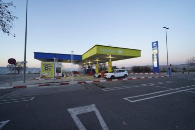 Rivas Vaciamadrid, İspanya. 7 Şubat 2025. Kapalı bir gölgelik altında yakıt ikmali yapan iki araçlı self servis Carrefour benzin istasyonu. Görüntü gün ışığında açık bir açık hava ayarı yakalıyor..