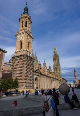 20 Nisan 2025. Zaragoza, İspanya. Zaragoza 'daki Bazilica del Pilar' ın dikey görüntüsü. Parlak mavi bir gökyüzünün altında yenileme ve onarım çalışmaları için kulelerin etrafında iskeleler var..