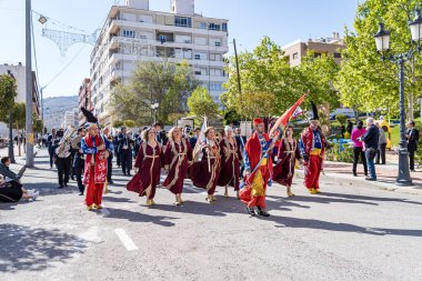 Onil, Alicante. 1 Mayıs 2025. Moors ve Hristiyanların Onil, Alicante 'deki geçit töreninin başlangıcında, yerel şenlikler sırasında renkli pankartlar taşıyan katılımcılar.