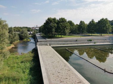 Segovia Köprüsü ve Prncipe Po yakınlarındaki Madrid Ro Parkı 'ndaki Manzanares Nehri manzaralı, ağaçlık yolları, çimenli kıyıları ve güneşli bir sabahta yansıtıcı suları var..