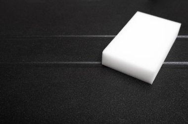 Beyaz melamin süngeri temizliyorum. Yeni granit mutfak lavabosu, siyah yıkama düzlüğü. Ev servisi. Üst görünüm.