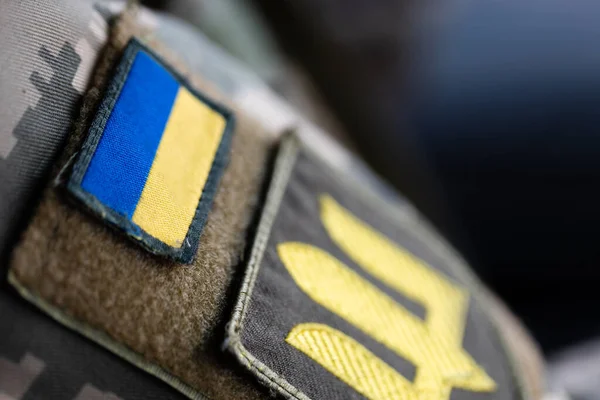 Ukrainian soldier in the army and flag, coat of arms with a golden trident on a military uniform background. Armed Forces of Ukraine.