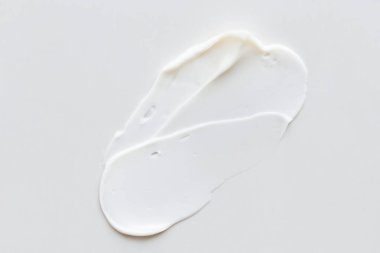 İzole edilmiş açık gri arka planda beyaz krem dokusu, yüz ve vücut için kozmetik. Smear.