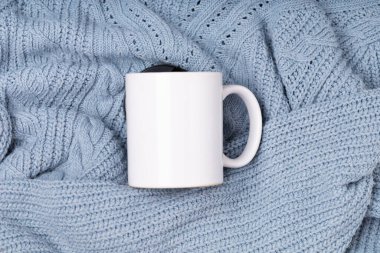 Beyaz boş kupa, tasarımın için fincan ve mavi süveter ve battaniye. Promosyon metni veya tanıtım içeriği için şablon boş