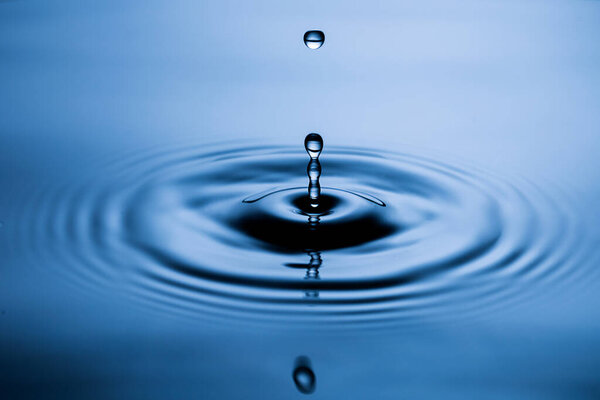 Blue Water drop falling, macro splash. Natural background.