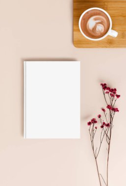 Kahveli ve kurutulmuş çikila çiçekli bej kapaklı beyaz bir cilt kapağı. İskandinav ya da wabi sabi stilinde dizayn ve reklamınız için boş şablon yatıyordu