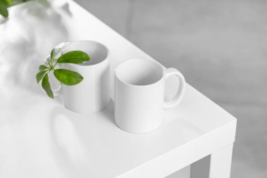 Beyaz bir çay fincanı ya da İskandinav tarzı bir mutfakta beyaz bir masada Scheffler bitkisiyle kahve fincanı. Tasarımınız için konu şablonu, kopyalama alanı ile reklam