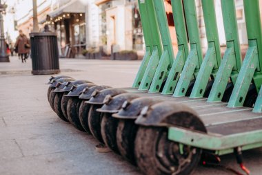 Kaldırımda bir sıra yeşil scooter.