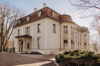 Kahverengi çatılı büyük beyaz bir bina.