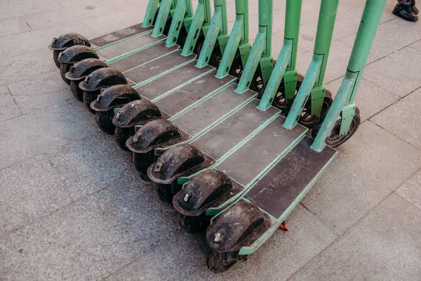 Kaldırımda bir sıra yeşil scooter.