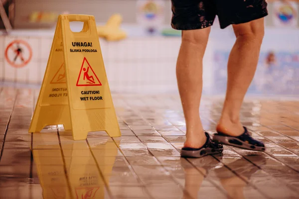 a wet floor with a caution sign on it