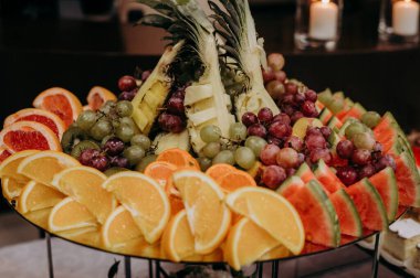 Tepesinde ananas olan bir tabak meyve.