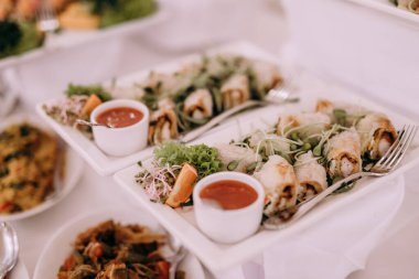 Tabaklar dolusu yemek ve soslarla dolu bir masa.