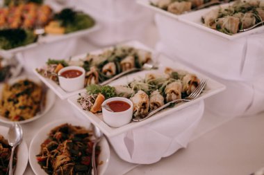 Tabaklar dolusu yemek ve çatal bıçakla dolu bir masa.