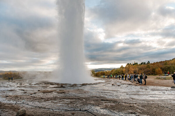 a group of people standing around a geyse