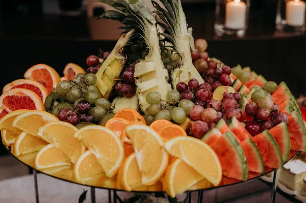 Tepesinde ananas olan bir tabak meyve.