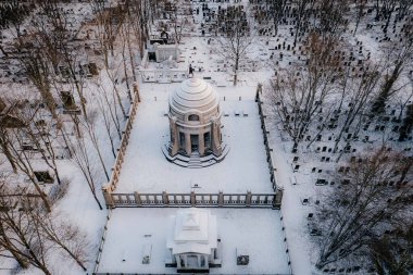 Üstünde kubbe olan karda bir mezarlık.