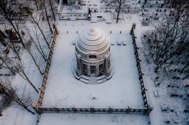 Karlı bir parkın ortasında kubbeli bir bina.