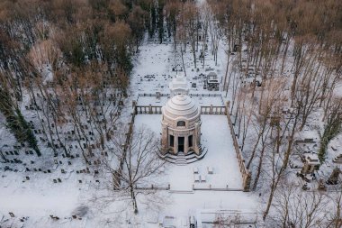 Karda ağaçlarla çevrili beyaz bir bina.
