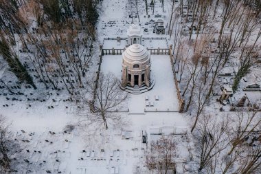 Ortada kubbe olan karlı bir mezarlık.