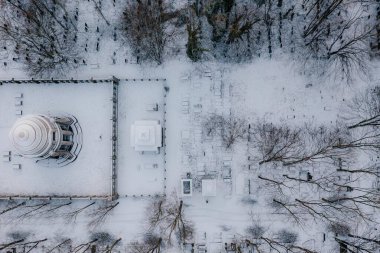 Karda ağaçlarla çevrili beyaz bir bina.