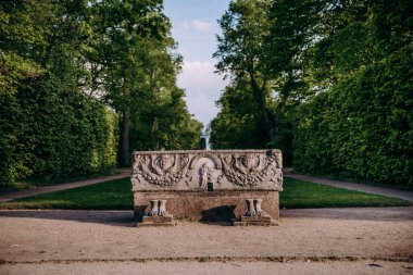 Arkasında ağaçlar olan bir parkta taş bir bank.