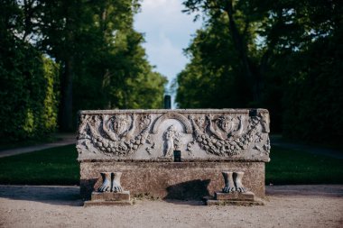 Taş bir bank, taş oymalı bir adam ve bir kadın.