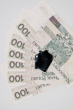 Bir yığın paranın üzerinde duran bir cep telefonu.