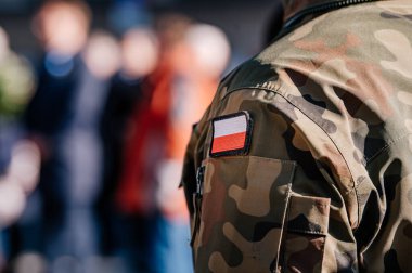 Sırtında bayrak olan askeri üniformalı bir adam.