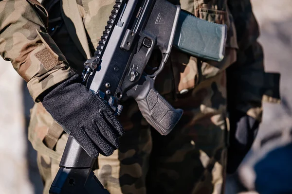 Kamuflajlı bir adam silah taşıyor.