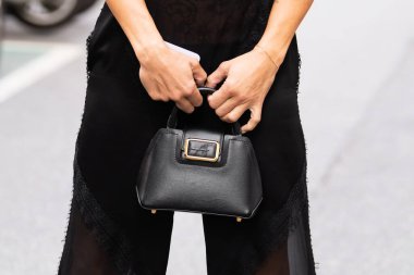 Milan, İtalya - 21 Eylül 2022: sokak tarzı kıyafet ayrıntıları, kadın siyah pantolon giyiyor, Alberta Ferretti 'den siyah parlak deri çanta.