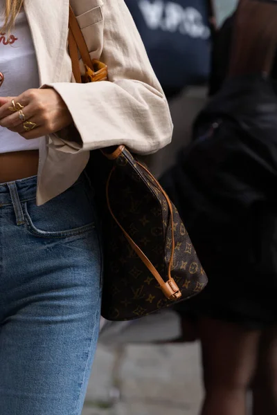 Milan, İtalya - 21 Eylül 2022: Sokak tarzı kıyafet ayrıntıları, kadın kahverengi LV monogram desenli bir el çantası giyiyor.