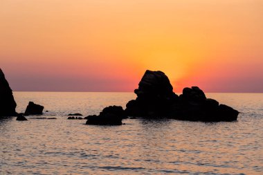 Beautiful view of orange sunset seascape with rocks in Italy. Tropical colourful sunrise landscape. Nature landscape. Tropical island coast